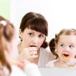 woman and little girl brushing teeth