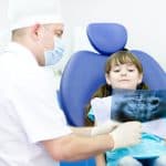 child looking at dental xray with dentist