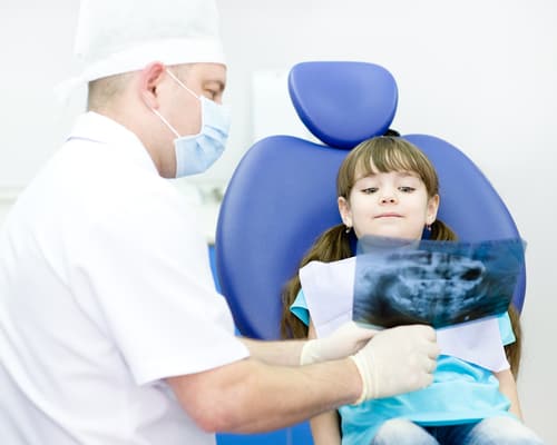 child looking at dental xray with dentist